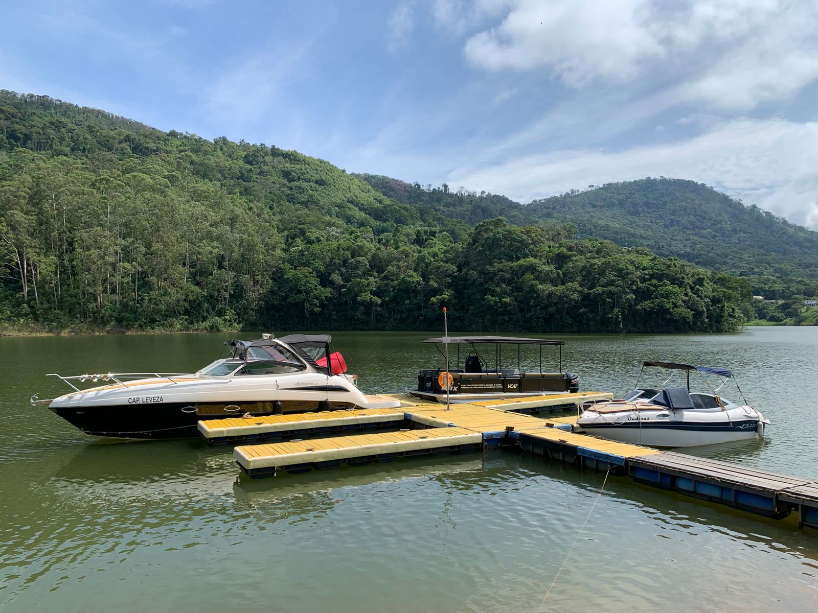 Boats docked on a lake surrounded by green hills