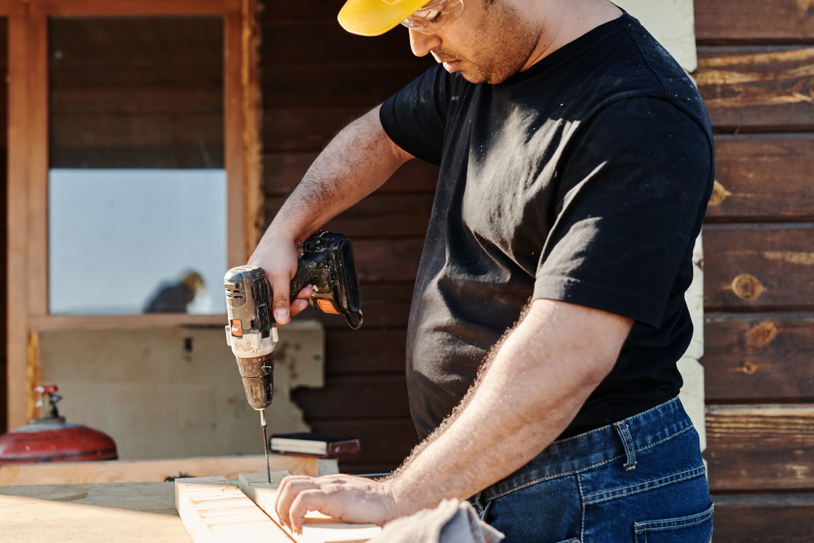Construction worker using a power drill on a wooden waterfront structure